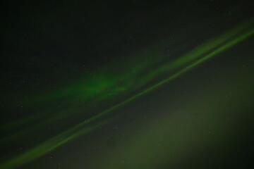  Soft green aurora borealis streaks gently across a starry night sky, creating a serene and...
