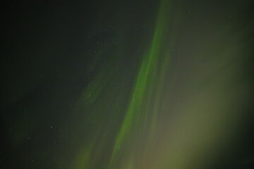  Soft green aurora borealis streaks gently across a starry night sky, creating a serene and celestial scene. Distant stars twinkle through the faint glow of the northern lights.