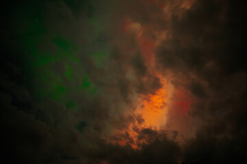 A captivating scene of the Aurora Borealis with vibrant red and orange hues illuminating the night sky. Dark clouds add drama, while subtle green light emerges through the atmosphere