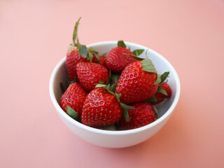 Red fresh strawberry in white bowl isolated on pink background