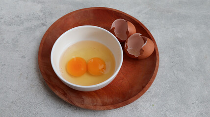 raw chicken eggs in a white bowl on the table, broken shells, the concept of cooking scrambled eggs, omelet, home cooking. copy space