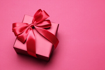 Gift box with bow on pink background, above view. Space for text
