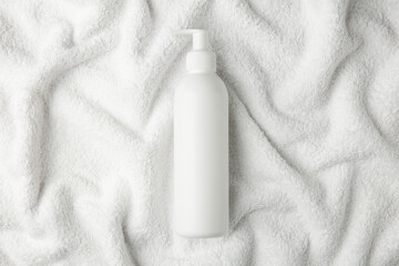 Bottle of shampoo on soft terry towel, top view