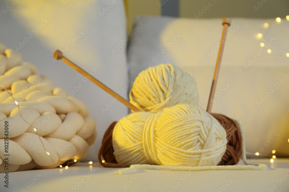 Wall mural Skeins of yarn, knitting needles and festive lights on sofa