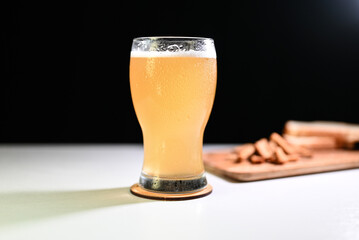 glass of beer on a light table in a pub with a snack on a dark background