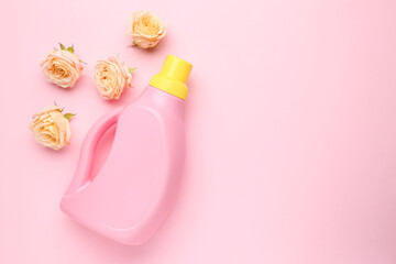Bottle of laundry detergent and flowers on pink background, closeup. Space for text