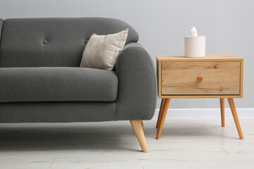 Comfortable sofa and table near grey wall in room