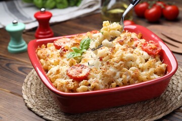 Eating delicious al forno pasta at wooden table, closeup