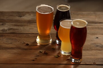 Glasses with different types of beer and pistachio nuts on wooden table