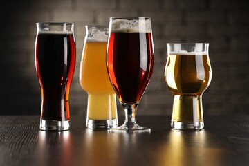 Glasses with different types of beer on wooden table in bar