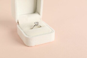 Beautiful ring with gemstone in box on pink background, closeup