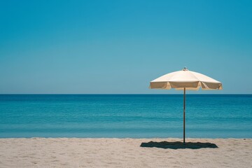 Lone umbrella on a serene beach under a clear blue sky.