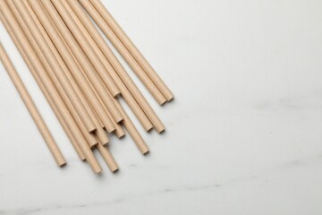 Bamboo drinking straws on light marble table, top view. Space for text
