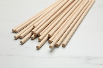 Bamboo drinking straws on light marble table, closeup
