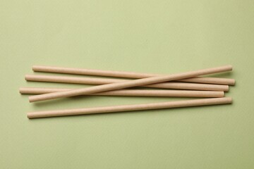 Bamboo drinking straws on green background, top view