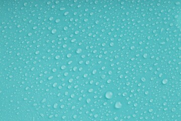 Water drops on turquoise background, top view