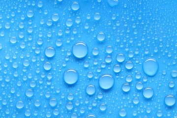 Water drops on blue background, top view