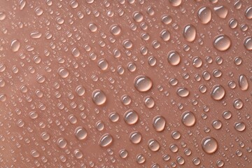 Water drops on brown background, top view