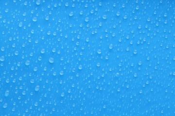 Water drops on blue background, top view
