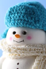 Cute decorative snowman against light blue background, closeup
