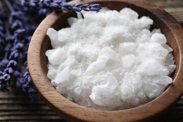 Natural sea salt in bowl and lavender on table, closeup