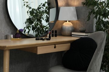 Mirror, dressing table, lamp, chair and houseplant indoors. Interior design