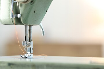 Sewing machine with thread on blurred background, macro view. Space for text