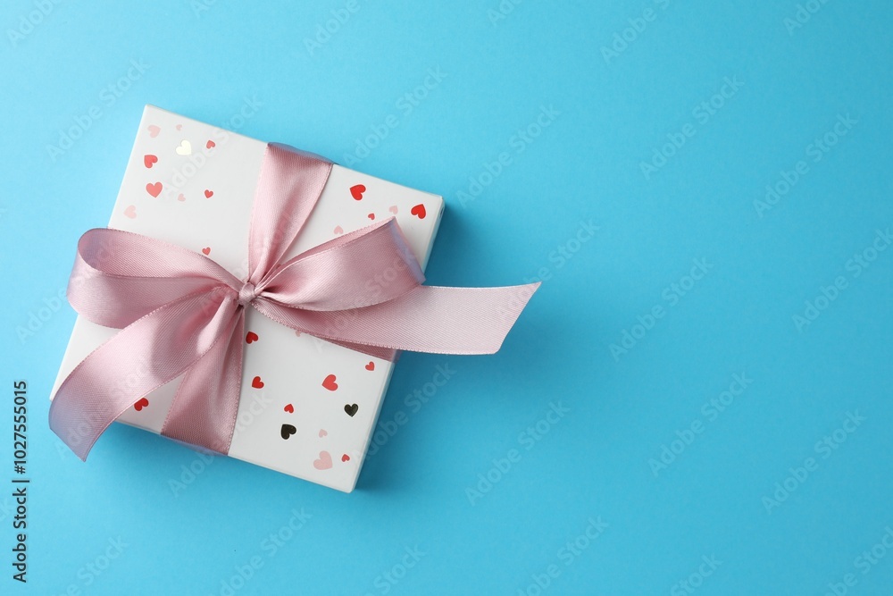 Sticker Gift box with bow on light blue background, top view. Space for text