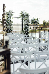 A wedding arch, decorated with flowers, stands on a podium, stands in the open air