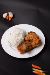 A spicy ayam geprek served with white rice and fresh chili. The crispy smashed chicken is coated in fiery sambal, creating a bold flavor. A perfect blend of crunch, heat, and savory goodness.
