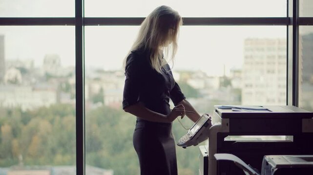 Woman using printer or scanner in office . Woman printing document	