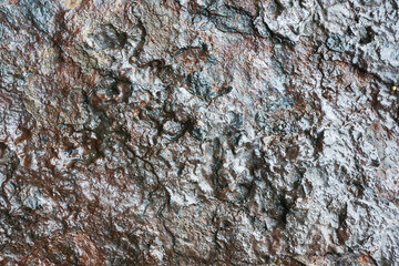 Wet rock background. Grunge texture of shiny stone. Steel-like appearance. Scratched and rough surface. Industrial black background. Dark stone and rock texture.