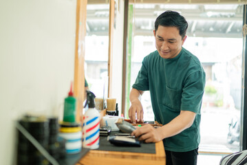 A man is currently standing at a barber shop where he is engaged in cutting a customers hair with great skill and precision