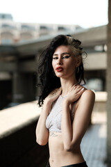 Portrait of alternative female rock star looking at camera with blurry buildings behind.