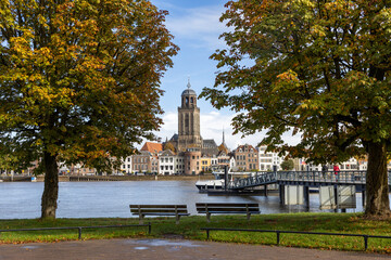 Autumn cityscape with the skyline of the city of Deventer on the river IJssel with ferries and the tower of the Lebuïnus Church