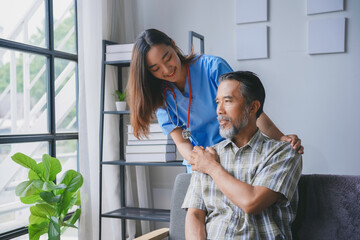 Obraz premium Young female nurse is comforting an elderly male patient at home by putting her hand on his shoulder while he sits on a chair