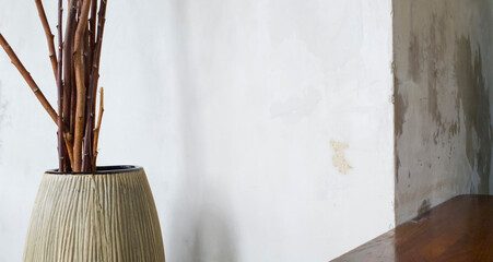 Blank concrete wall corner paired with an artistic pot with dried branches, for vintage decor themes or traditional interiors. Ideal for home decor inspiration and photo or painting frame mockups