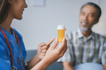 Female doctor is holding a pill bottle while explaining the prescription to a senior male patient