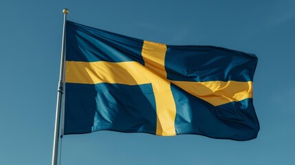 The Swedish flag, a blue field with a yellow cross, waving in the wind.
