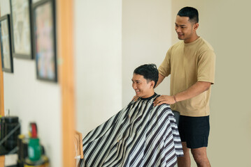 Fototapeta premium A man is currently having his hair expertly cut by a skilled barber inside a busy and lively barbershop filled with activity