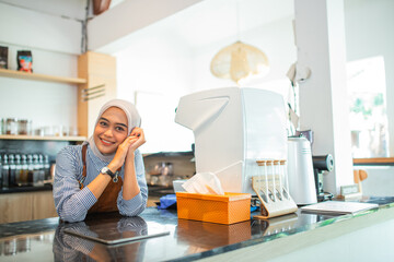 Indonesian woman in hijab shop owner sitting in coffee shop