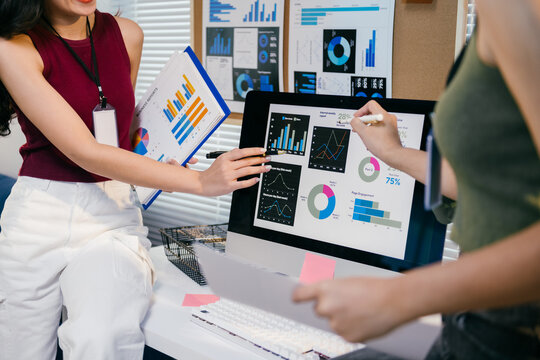 Team of marketing specialists is having a meeting, analyzing financial data and graphs on a computer screen. They're discussing new strategies based on the latest statistics