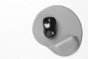 Computer mouse and mousepad with armrest on white table, top view. Space for text