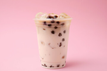 Tasty milk bubble tea in plastic cup on pink background