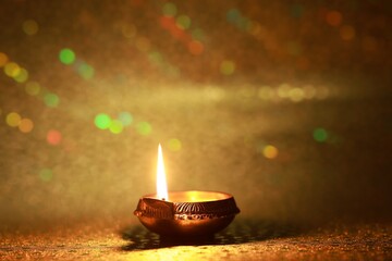 Diwali celebration. Diya lamp on golden background. Space for text