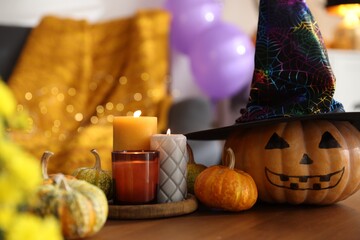 Burning candles and pumpkins on wooden table indoors. Halloween celebration