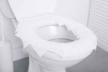 Toilet seat with paper tissues in bathroom