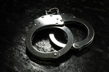 Metal chain handcuffs on black table, closeup