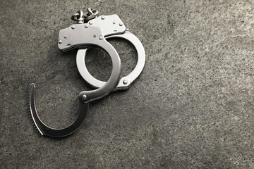 Classic chain handcuffs on grey table, space for text