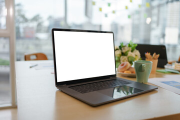 Open laptop is sitting on a desk in a modern office, the screen is blank and ready for your mockup